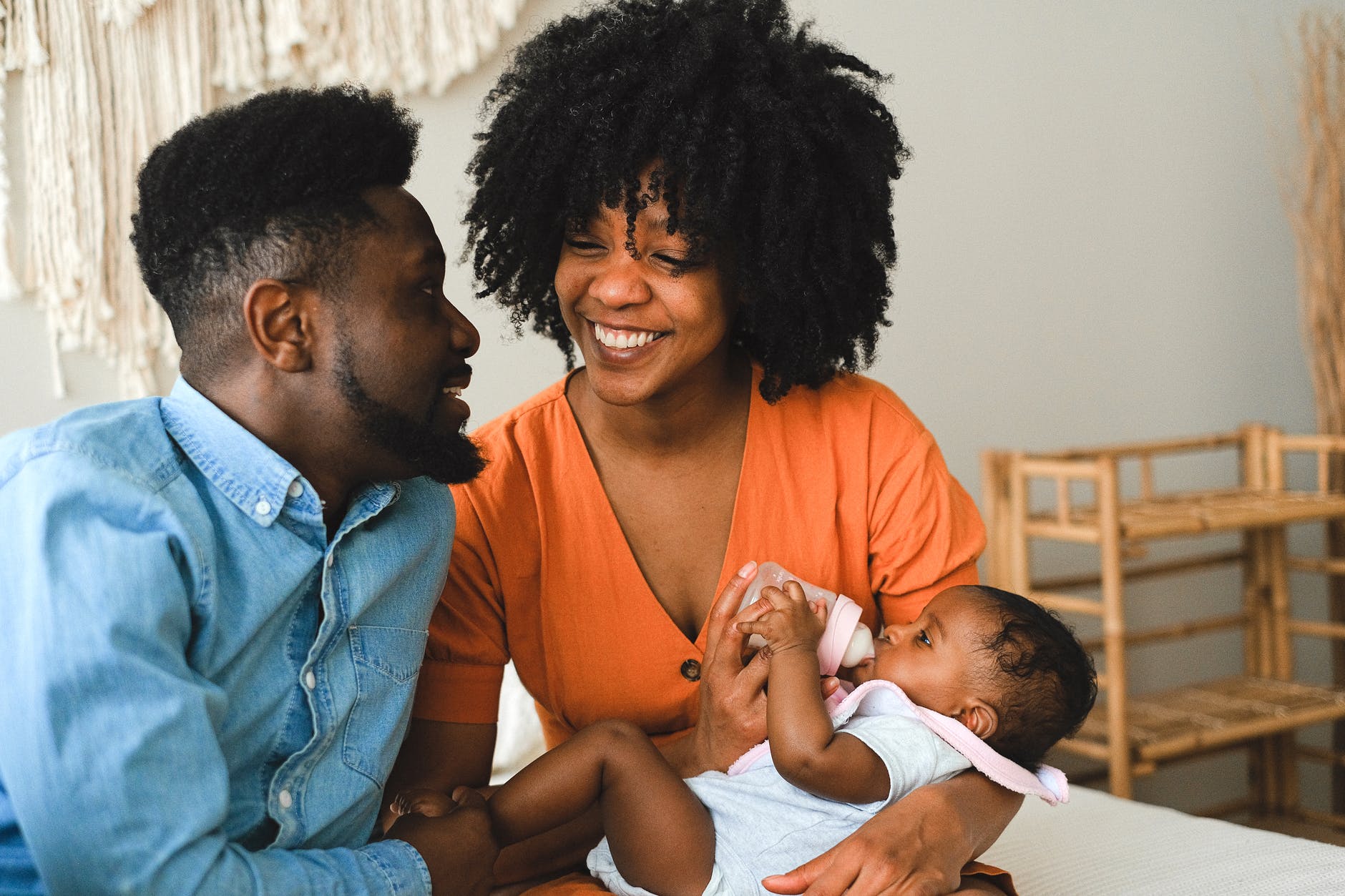 happy couple sitting on bed carrying a baby
